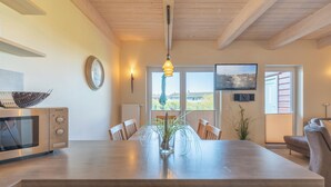 A modern kitchen with a central island, wooden cabinets, a microwave, and a dining area with chairs and a table.