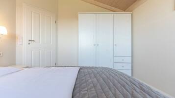 A bedroom with a bed, a wardrobe, and a wall-mounted light fixture.