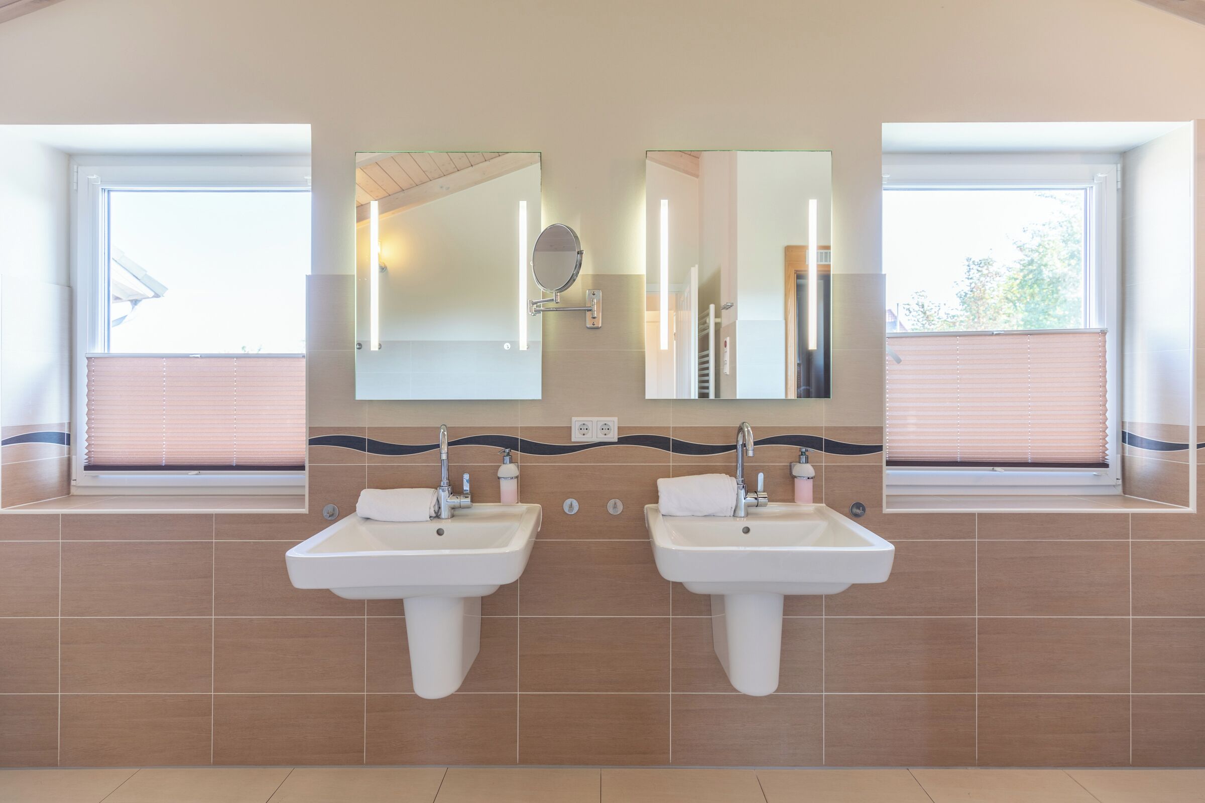 A bathroom with two sinks, mirrors, and a window with blinds.