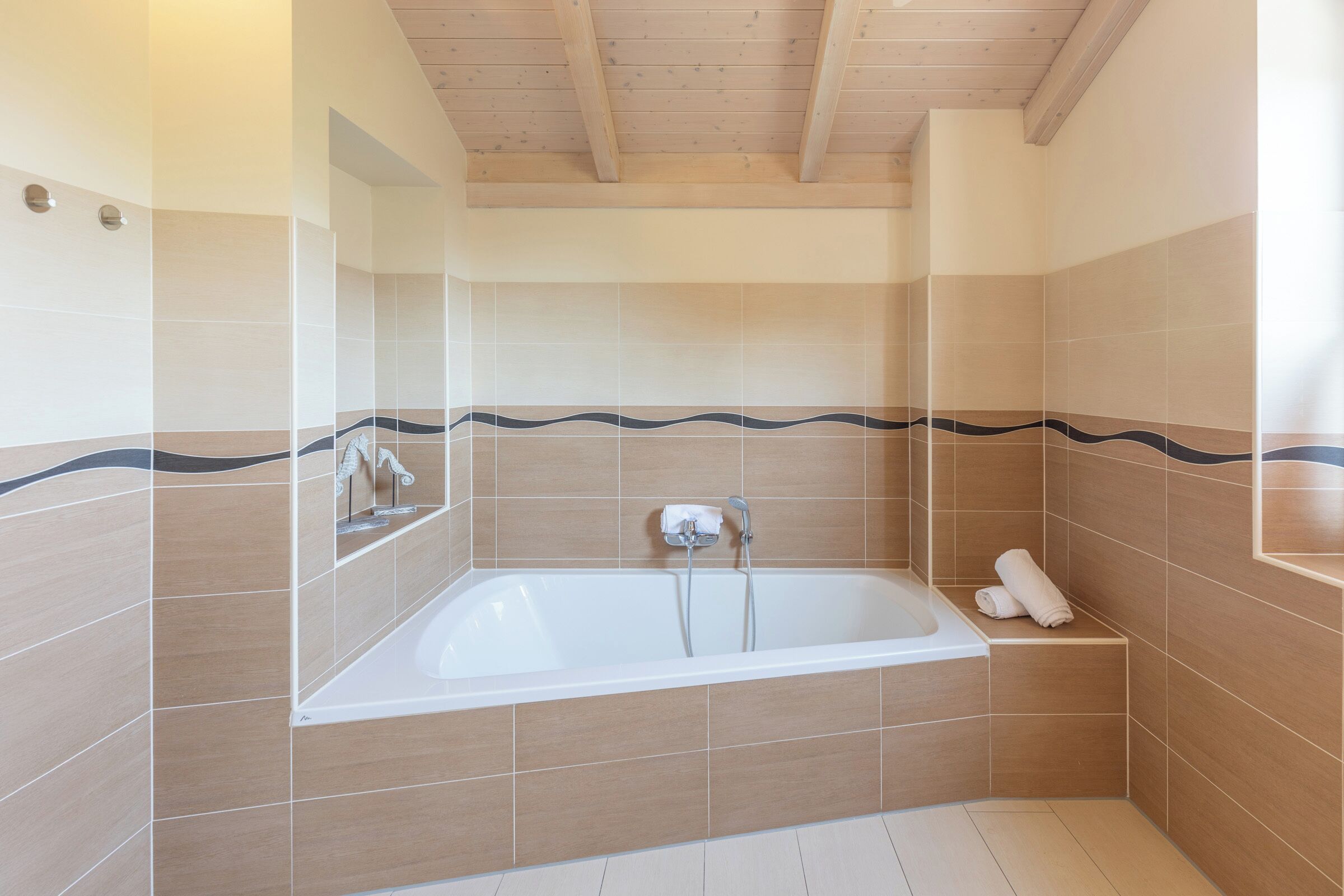 Ein modernes Badezimmer mit einer freistehenden Badewanne, gefliesten Wänden und einer Holzbeschichtung an der Decke.