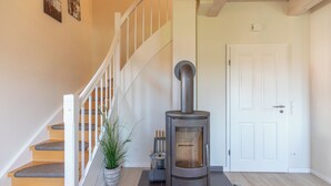 A modern interior with a wooden staircase, a wood-burning stove, and a white door.