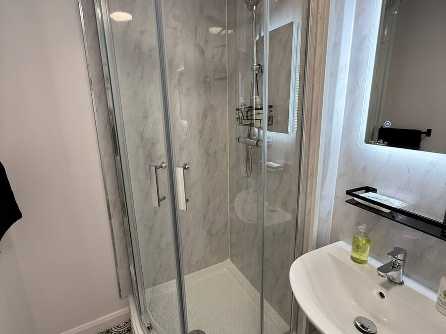 Une salle de bain moderne avec une douche à parois de verre, un lavabo blanc et un miroir au-dessus.