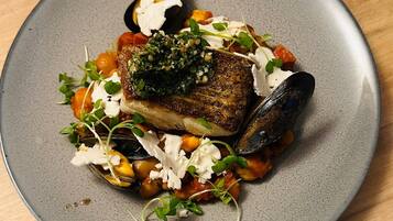 A plate of food with a piece of fish, mussels, and vegetables.