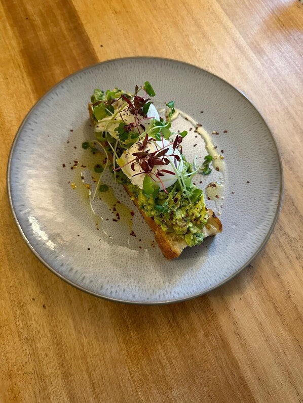 A plate with a food item topped with greens and a dollop of cream. - The White Hart (Melksham)