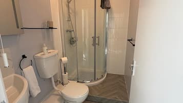 Une salle de bain moderne avec une douche à parois de verre, des toilettes, un lavabo et un miroir.