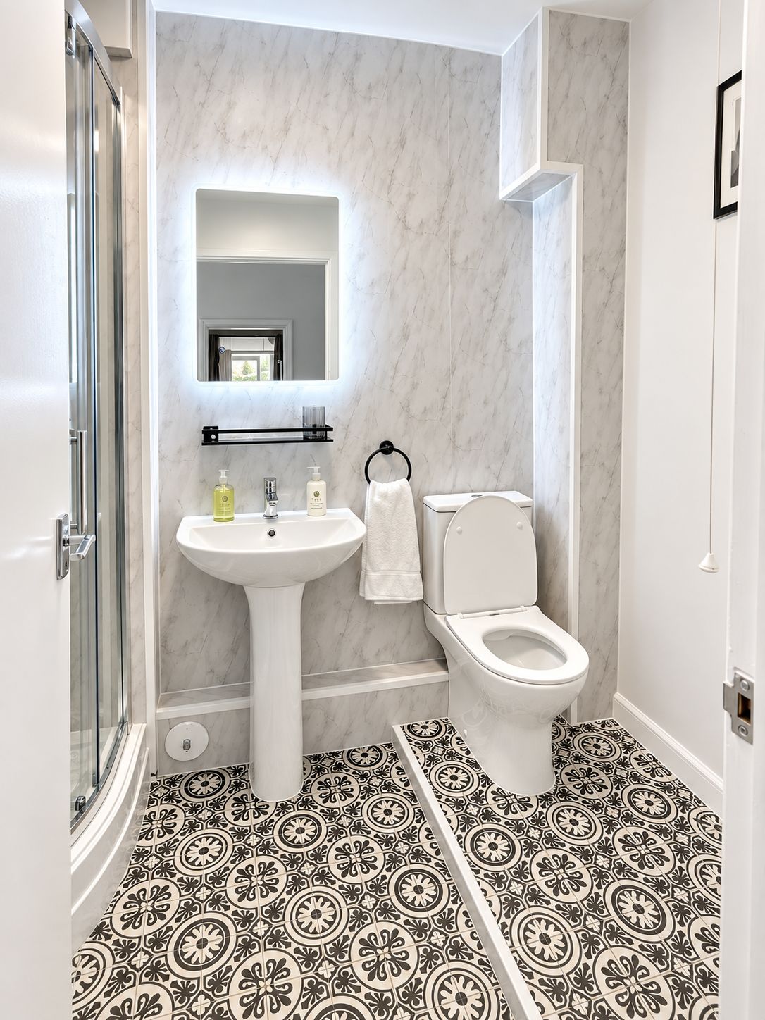 A bathroom with a white sink, toilet, and a glass shower enclosure.