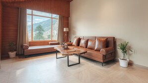 Un salon moderne avec un plafond en bois, un canapé en cuir marron, une table basse en bois et une grande fenêtre donnant sur une vue imprenable sur les montagnes.