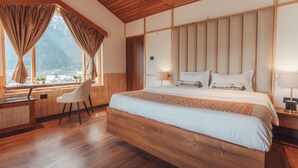 Une chambre spacieuse avec un grand lit, une tête de lit en bois et un bureau avec une chaise.