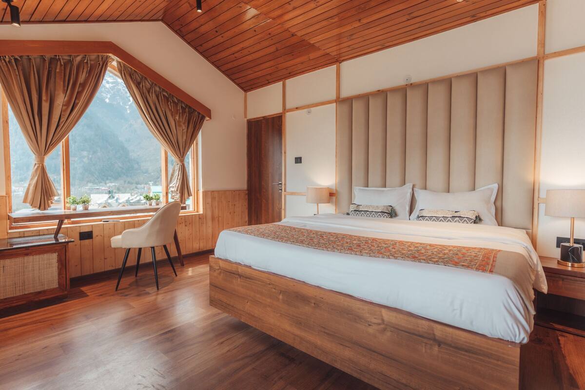 A spacious bedroom with a large bed, wooden headboard, and a desk with a chair.