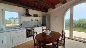 A modern kitchen with white cabinets, a stainless steel range hood, and a large window overlooking a garden. - Mondomini Panoramic Cottage, stunning view on sea, hills and 8500 olive trees (Marche)