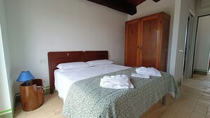 A bedroom with a wooden bed, a wardrobe, and a blue lamp. - Mondomini Panoramic Cottage, stunning view on sea, hills and 8500 olive trees (Marche)