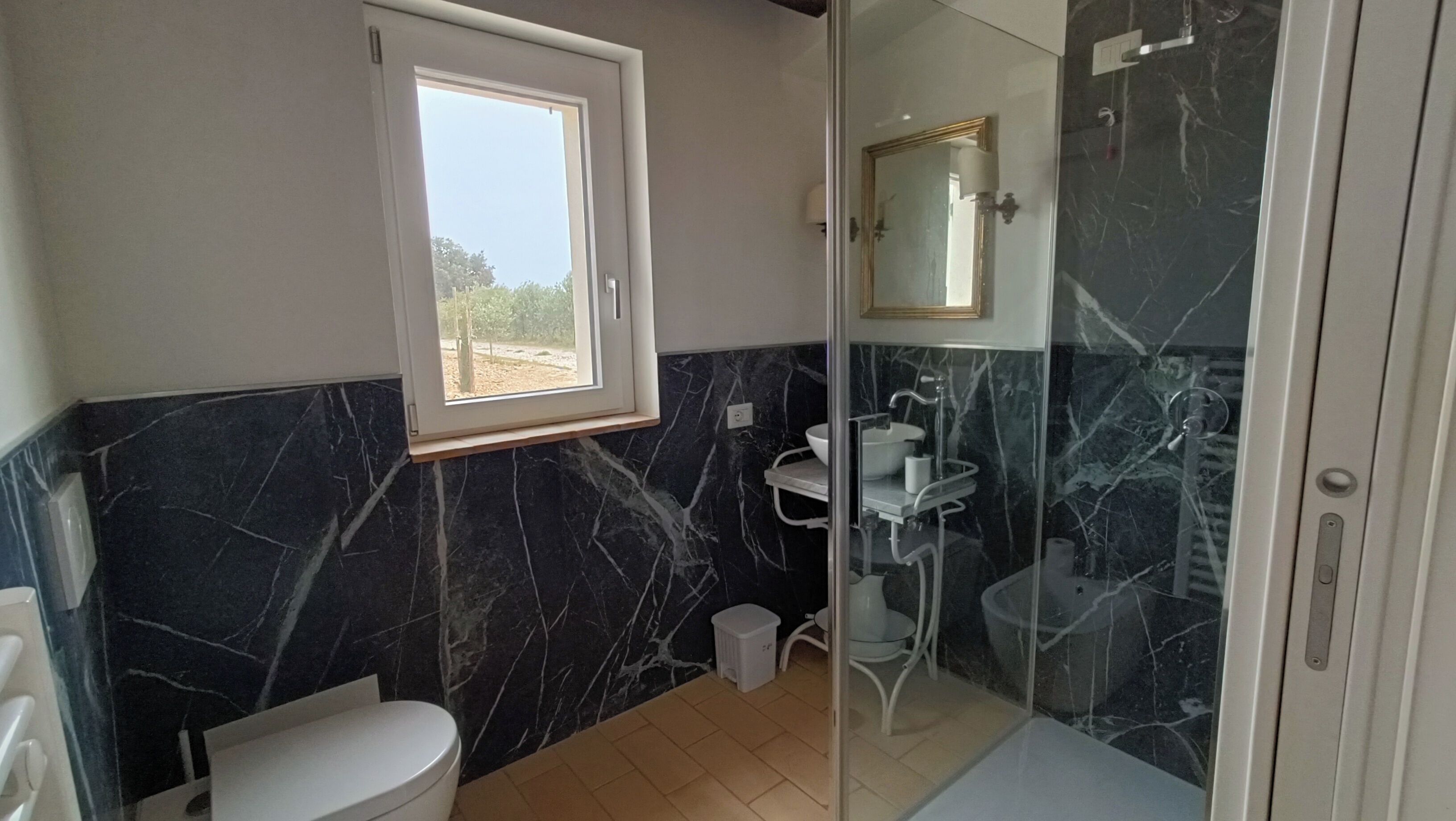 Une salle de bain comprenant des toilettes, un lavabo et une douche séparée par une paroi en verre.