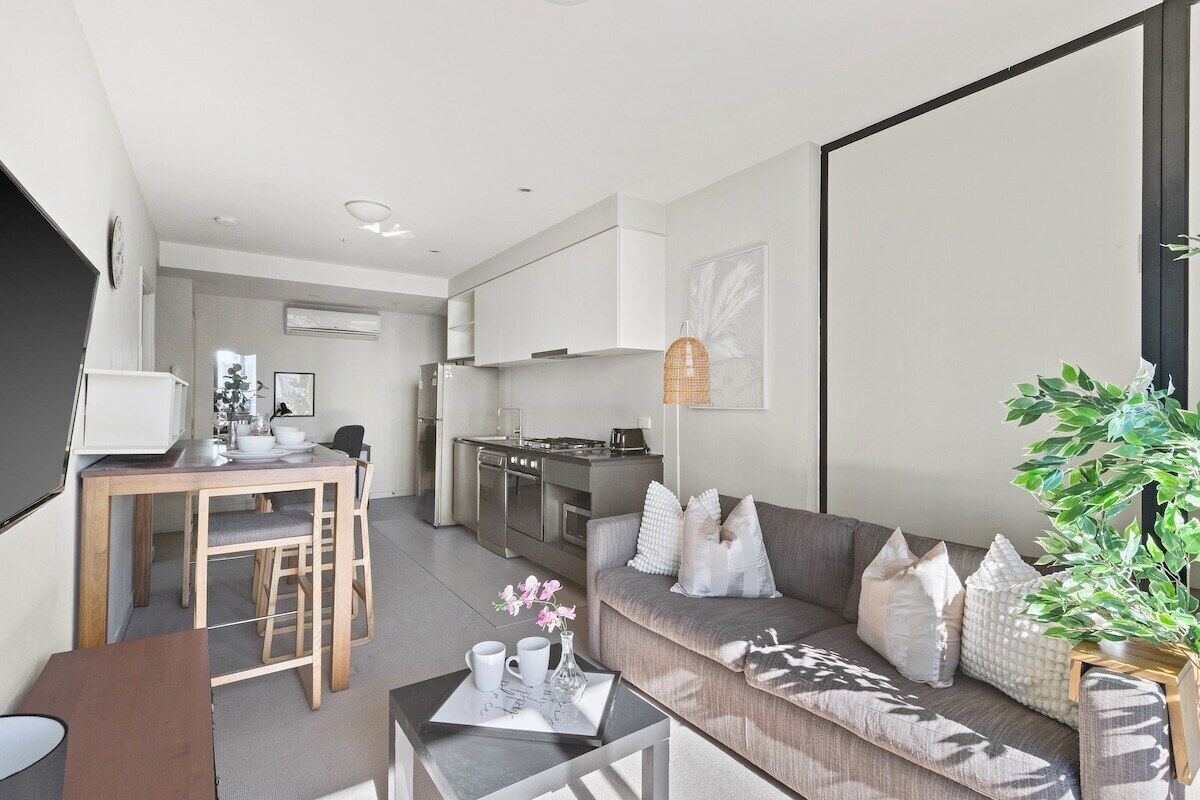 A modern apartment with a dining area, kitchenette, and a living room with a sofa and a coffee table.