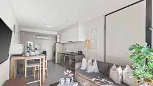 Um apartamento moderno com área de refeições, cozinha compacta e sala de estar com sofá e mesa de centro.