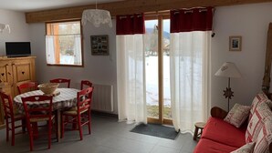 Een eethoek met een tafel en stoelen, een bank, een lamp en uitzicht op de omgeving.