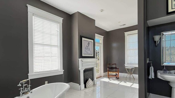 A modern bathroom with a freestanding bathtub, a fireplace, and a large window providing natural light. - Elegant Historic Home, Steps from Forsyth (Savannah)
