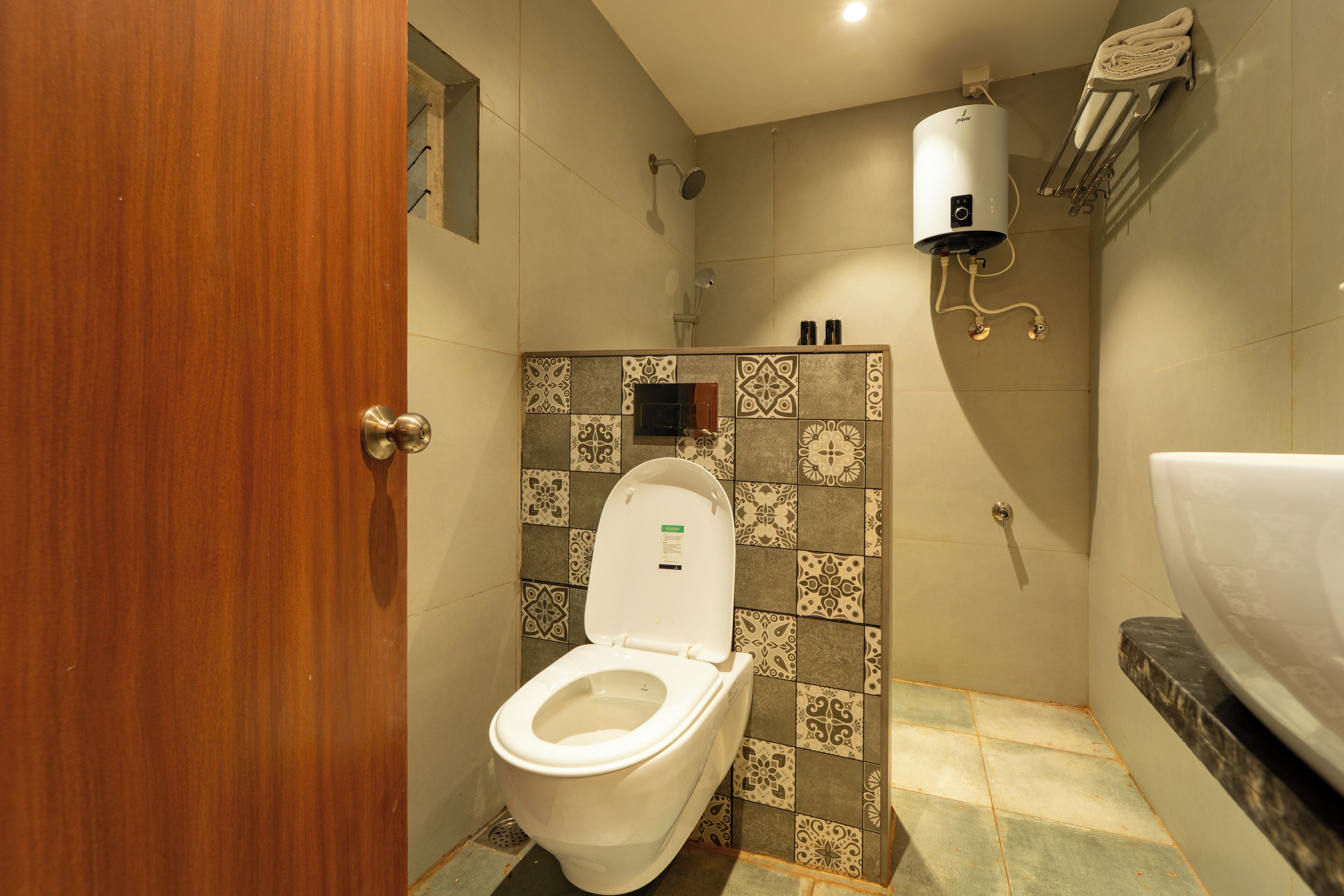 A bathroom with a toilet, shower, and a towel rack.