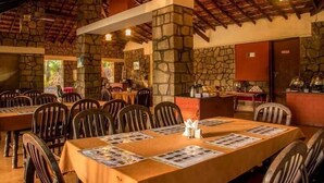 A restaurant with stone walls, wooden tables, and chairs. - Bison River Resort Dandeli (Joida)