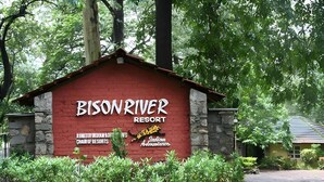 A red building labeled "Bison River Resort" with a stone wall and greenery around it. - Bison River Resort Dandeli (Joida)