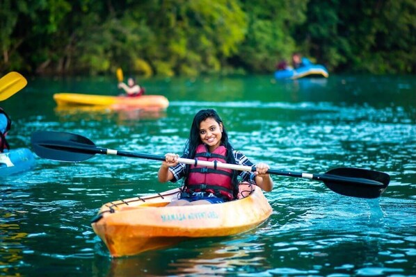 A person kayaking on a calm river surrounded by greenery. - Bison River Resort Dandeli (Joida)