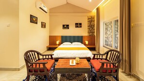 A hotel room with a bed, two bedside tables, a table with chairs, and artwork on the walls. - Bison River Resort Dandeli (Joida)