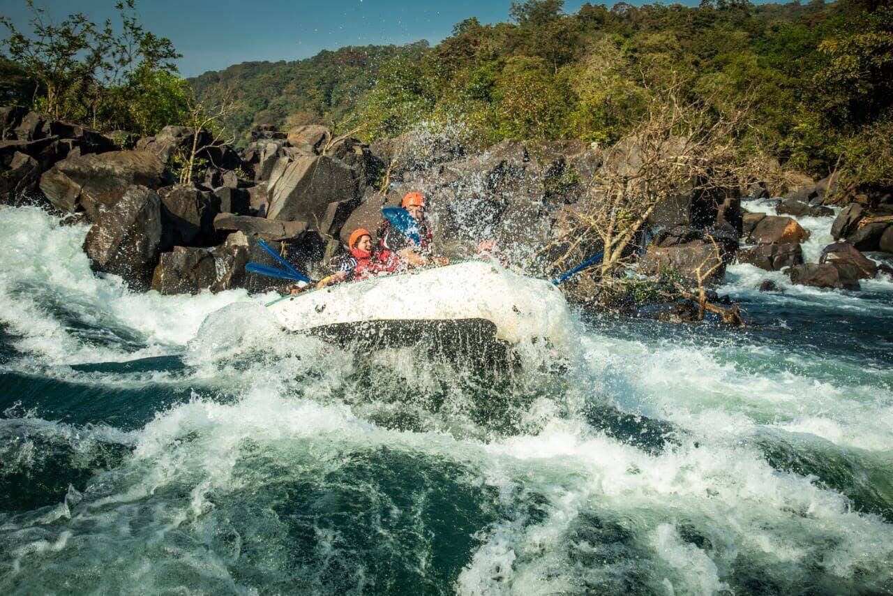 A white raft navigating through a river with rocks and rapids.