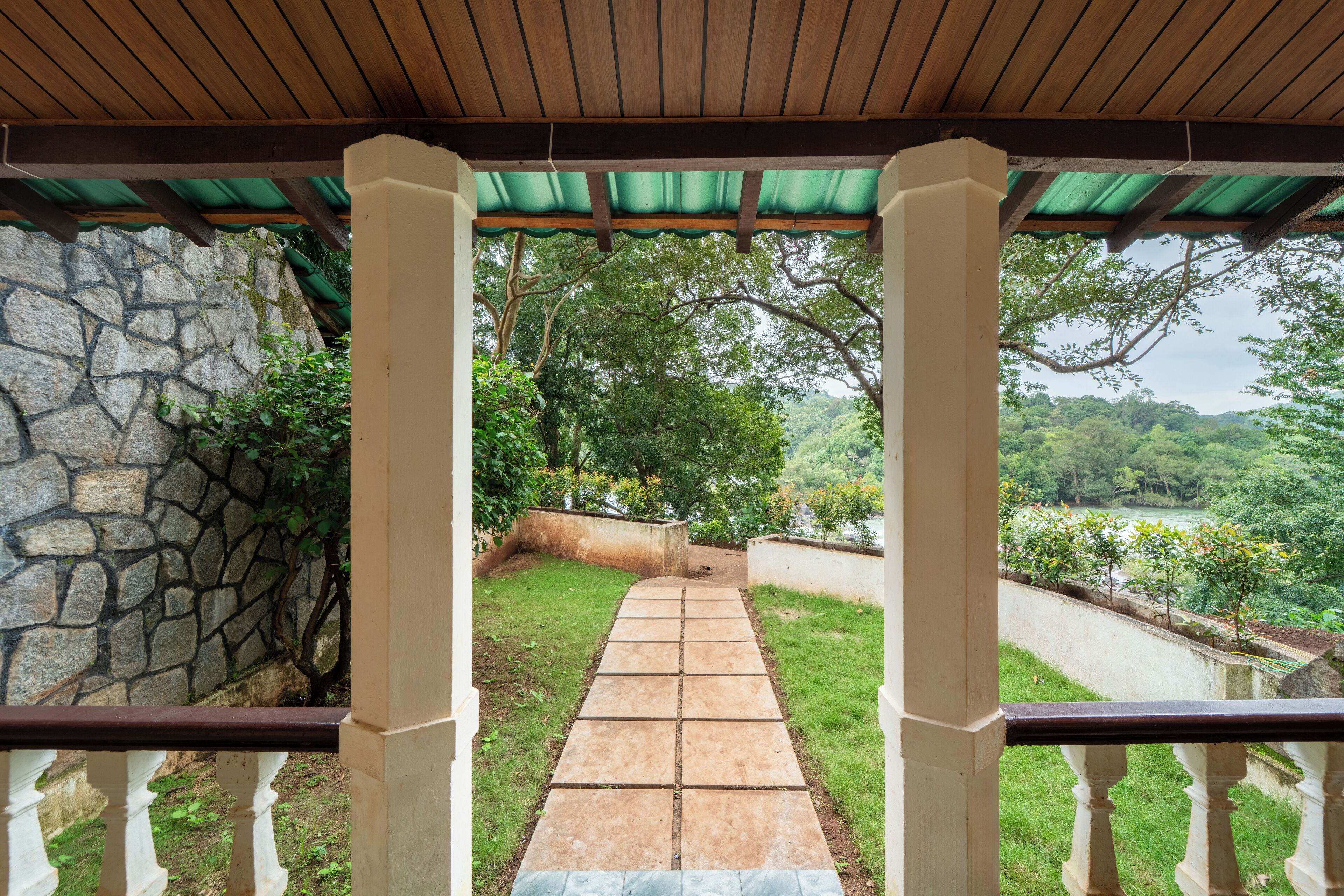 A stone wall, a paved pathway, and a view of a lush green landscape.