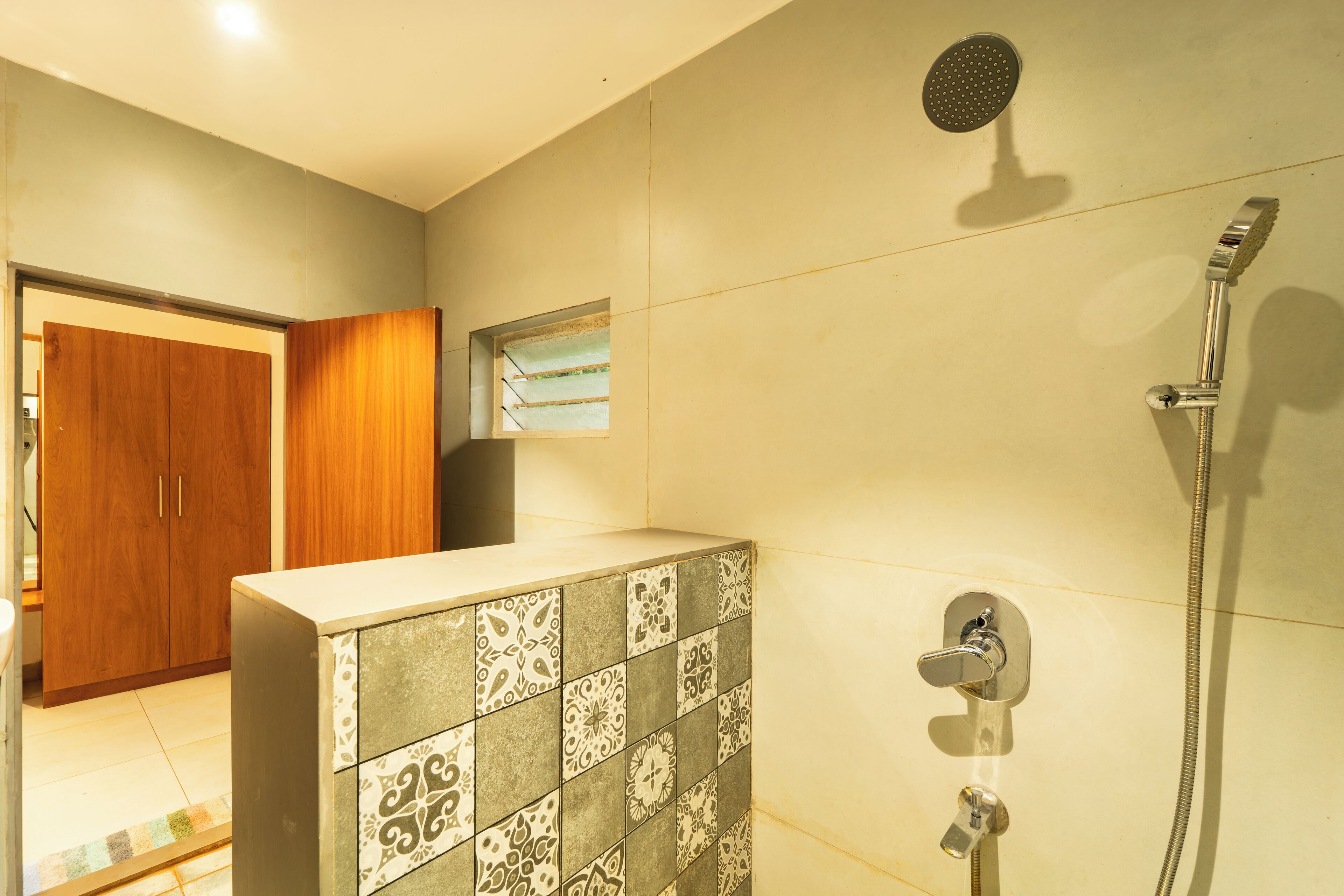 A bathroom with a shower, tiled walls, a wooden door, and a mirror.