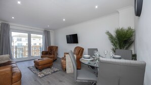 Una sala de estar moderna con un sofá, sillones y una mesa de comedor lista para dos personas.