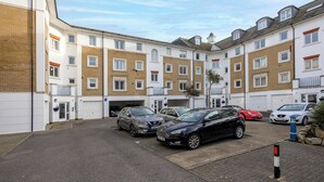 Un edificio residencial de varios pisos con una zona de estacionamiento.