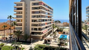 Un hotel de varios pisos con balcones, piscina y vista al mar.