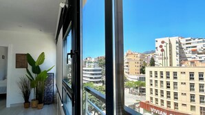 Un balcón con vistas a un paisaje urbano, incluyendo un edificio con la señalización 'Las Dalias'.