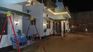 A two-story building with a balcony, a swing set, and a patio area. - Rithu's inn (Tirupattur)