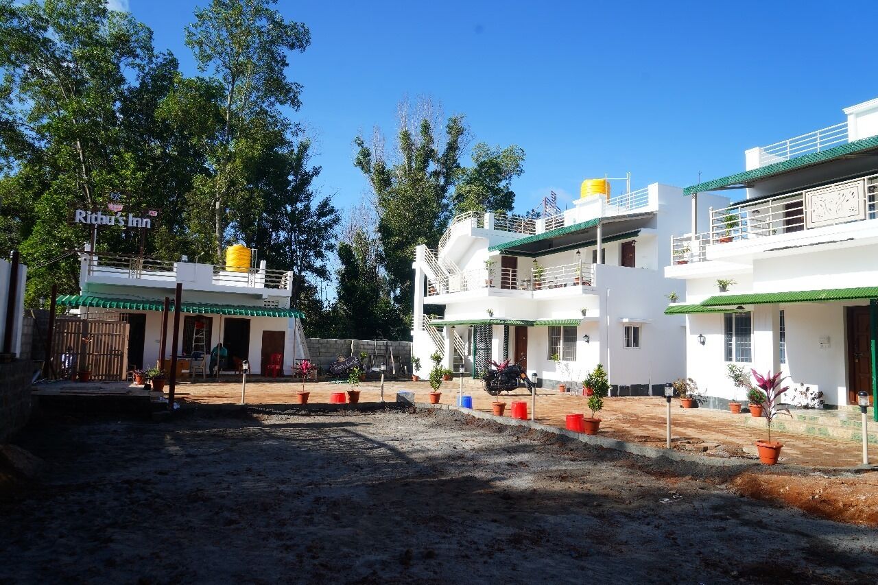 A hotel with a green roof, white walls, and a sign reading "Rithu's Inn".