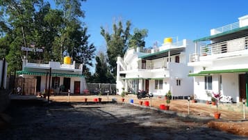 A hotel with a green roof, white walls, and a sign reading "Rithu's Inn".