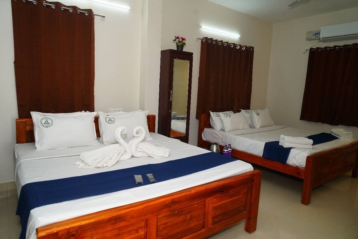 A hotel room with two wooden beds, white bedding, and a blue bed runner.
