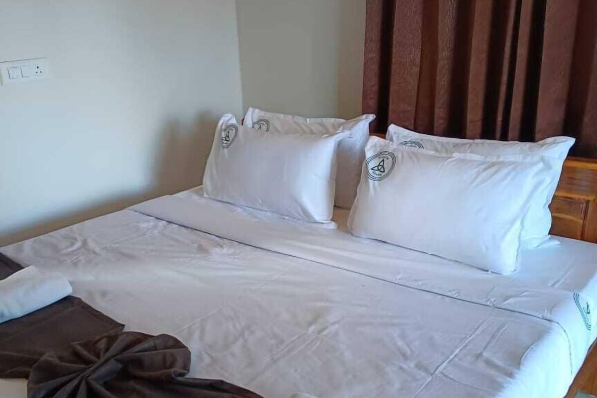 A neatly made bed with white linens, two pillows, and a folded towel.