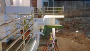 A modern two-story building with a balcony, a swing set, and potted plants. - Rithu's inn (Tirupattur)