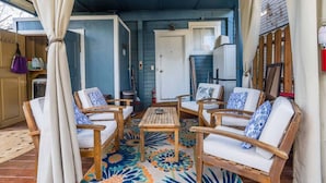 Une véranda couverte, dotée de meubles en bois, d’un tapis à motifs et d’un ventilateur de plafond.