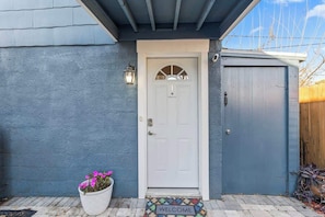 A house with a white door, a welcome mat, and a potted plant. - Mid-Century Modern Riverside | Team Joseph Ellen (Jacksonville)