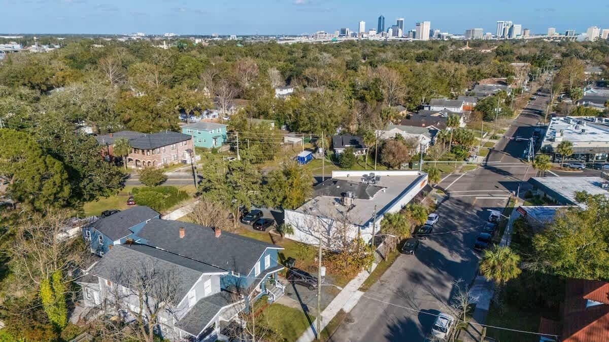 An aerial view of a residential area with houses, streets, and a distant city skyline.