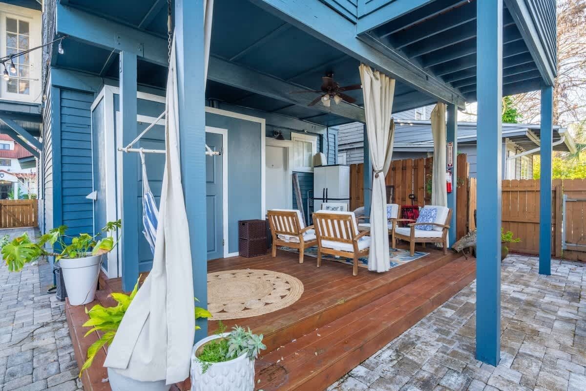 A covered porch with wooden flooring, a ceiling fan, and a seating area with two chairs and a table.