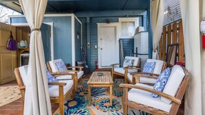 A covered porch with wooden chairs and a table, a door, and a ceiling fan. - Mid-Century Modern Riverside - Team Joseph Ellen (Jacksonville)