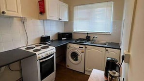 A compact kitchen with a stove, oven, washing machine, and a small sink. - Walthamstow - Apartment - Stay 3 - Street Parking (London)