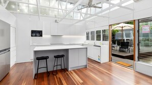 A modern kitchen with white cabinetry, a central island with stools, and a view to an outdoor deck.