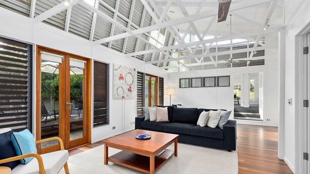 A spacious living area with a high ceiling, large windows, and a modern design.