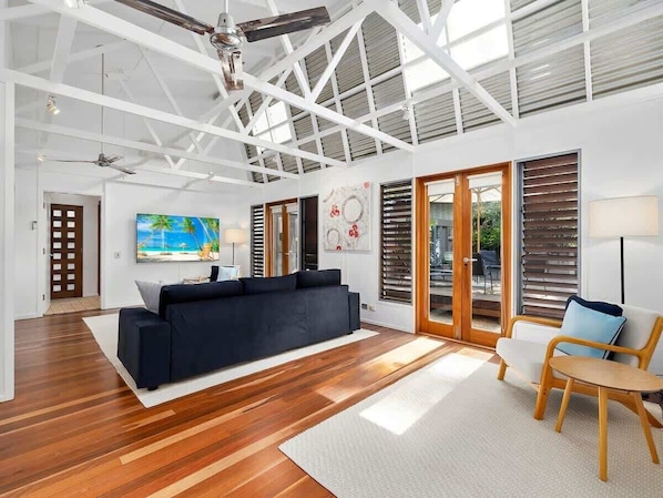 A spacious living area with a black sofa, a wooden coffee table, and a TV.