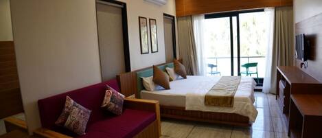 A hotel room with a bed, a sofa, a desk, and a TV.