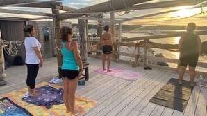 A wooden deck with exercise mats, ropes, and a view of the sunset over water. - Casa Chicchella (Vieste)