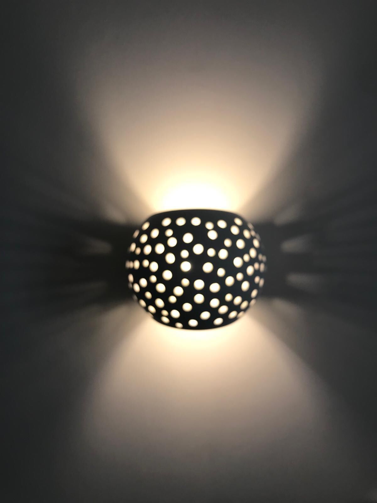 A spherical light fixture with a pattern of evenly spaced holes.